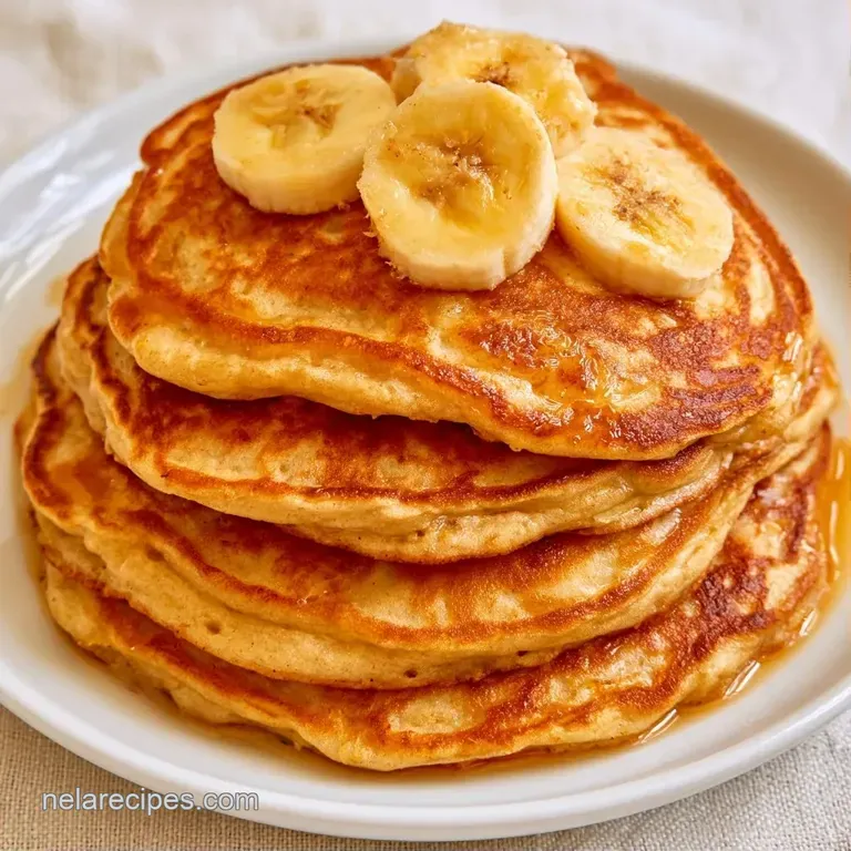 Golden-brown pancakes on a white plate with a drizzle of amber maple syrup and a handful of fresh blueberries.